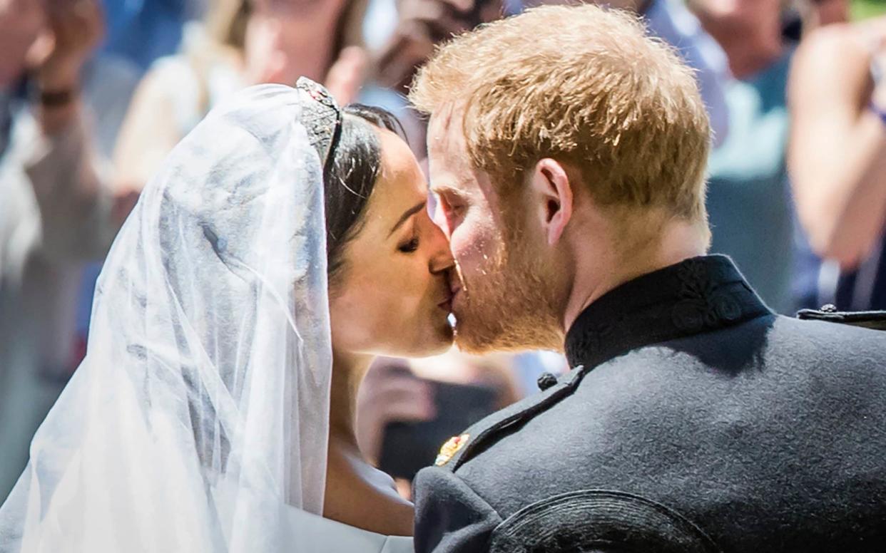 Britain's Prince Harry, Duke of Sussex kisses his wife Meghan, Duchess of Sussex as they leave from the West Door of St George's Chapel - AFP