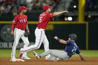 Texas Rangers shortstop Corey Seager (5) throws to first to complete a double play after forcing out Seattle Mariners' Dylan Moore (25) at second, as second baseman Marcus Semien, left, watches during the sixth inning of a baseball game Friday, July 15, 2022, in Arlington, Texas. Sam Haggerty was out at first. (AP Photo/Tony Gutierrez)