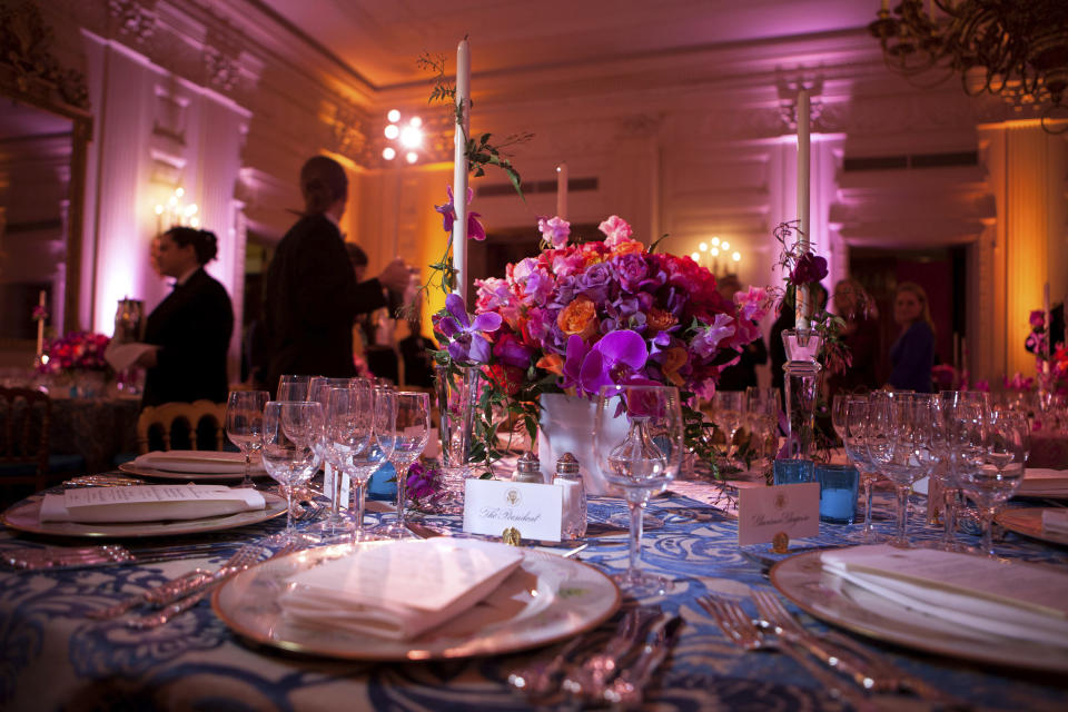 In this Feb. 27, 2011 photo provided by Stichting Kunstboek, a vivid bouquet of orange and fuchsia flowers with accents of hot pink phaleonopsis orchids makes a strong statement for the annual National Governors Association Dinner at the White House state dining room in Washington. The historic "Charleston" candlesticks are wrapped with blooming jasmine vine. The Lady Bird and President Johnson china service, featuring wildflowers from across America, reflects the gathering of Governors from all 50 states. The photograph is featured in the book "Floral Diplomacy: At the White House," by Laura Dowling. (Chuck Kennedy/The White House/Stichting Kunstboek via AP)