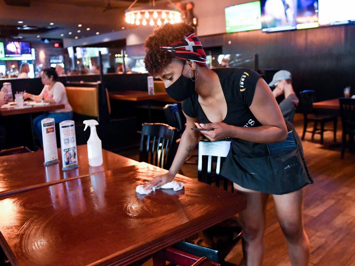 Restaurant server wipes down table at P.J. Whelihan's restaurant and pub in Spring Township Friday evening June 25, 2021