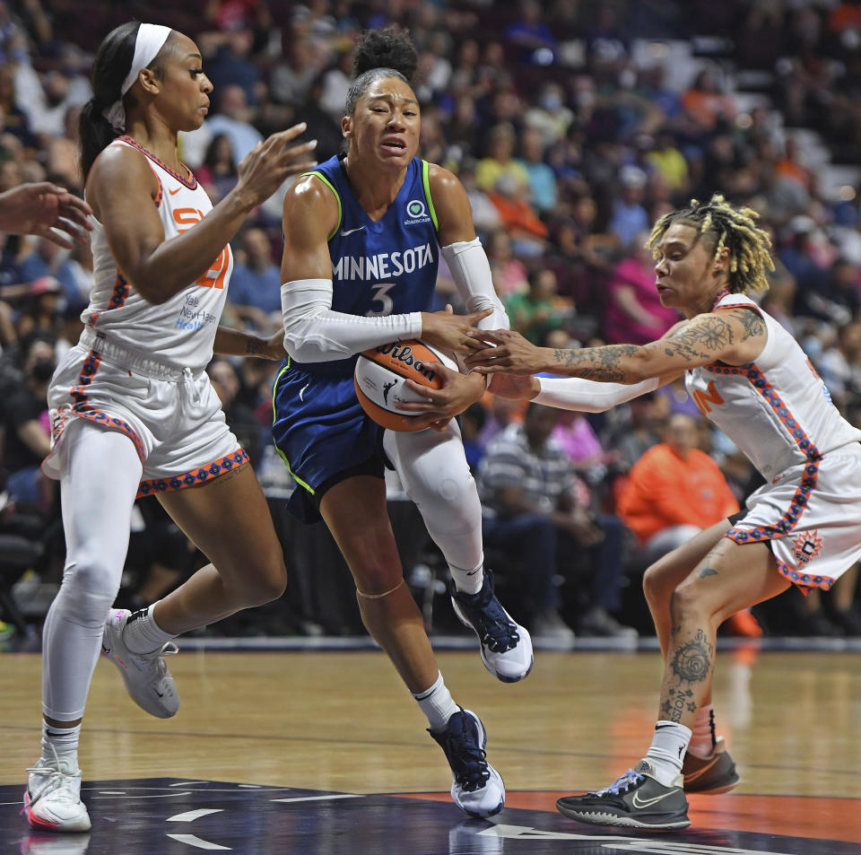 Minnesota Lynx forward Aerial Powers (3) drives between Connecticut Sun defenders DiJonai Carrington, left, and Natisha Hiedeman, right, during a WNBA basketball game Sunday, Aug. 14, 2022, in Uncasville, Conn. (Sean D. Elliot/The Day via AP)