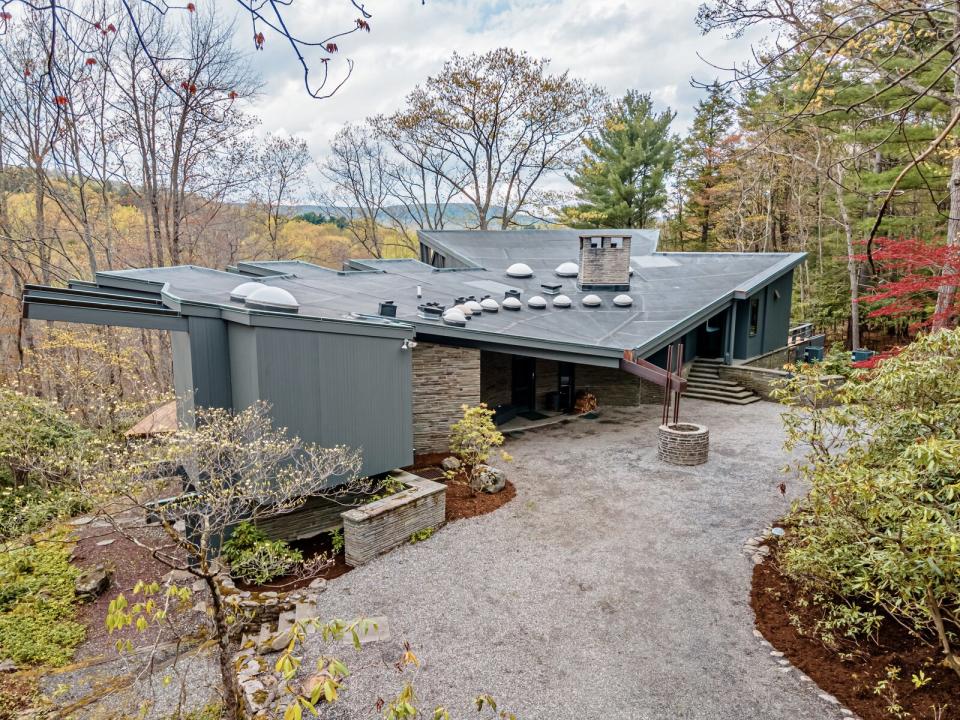 Architect John Michael drew inspiration from Frank Lloyd Wright as he designed the wedge-shaped home, which overlooks the surrounding woods with walls of glass.