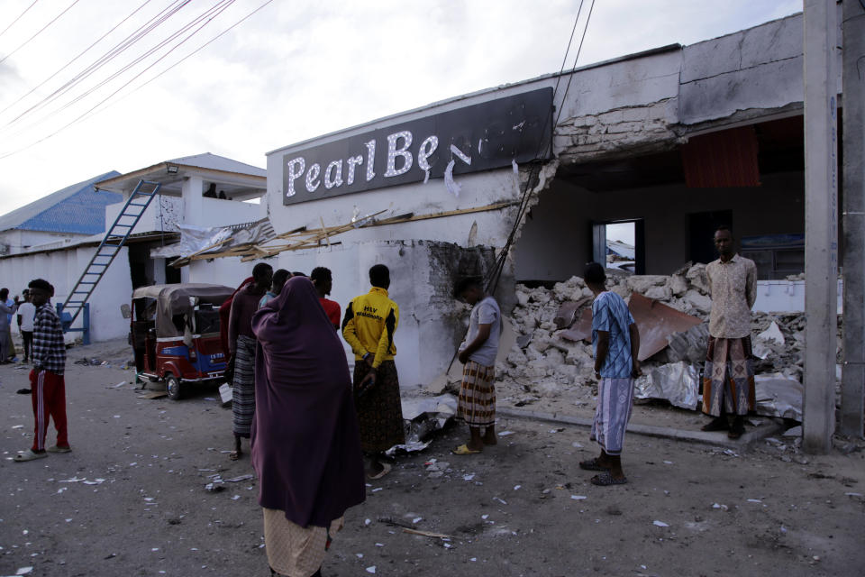 Somalis stand stand outside the destroyed Pearl Beach hotel in Mogadishu, Somalia, Saturday, June 10, 2023. Witnesses and state media in Somalia say extremists have attacked the beachside hotel in the capital, Mogadishu, and security forces are responding at the site as some people remain trapped inside.(AP Photo/ Farah Abdi Warsameh)