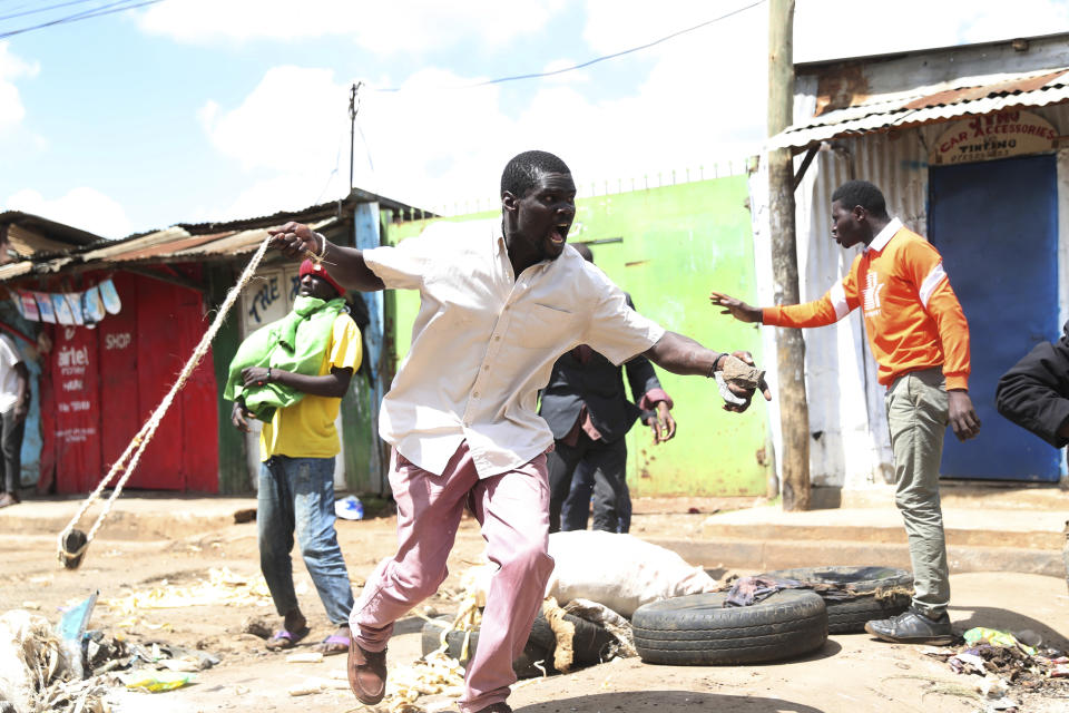 A protester throws a stone towards police officers during a mass rally called by the opposition leader Raila Odinga over the high cost of living in Kibera Slums, Nairobi, Kenya, Monday, March 27, 2023. Police in Kenya are on high alert ahead of the second round of anti-government protests organized by the opposition that has been termed as illegal by the government. Police chief Japheth Koome insists that Monday's protests are illegal but the opposition leader Raila Odinga says Kenyans have a right to demonstrate.(AP Photo/Brian Inganga)