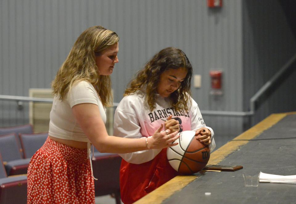 Olivia Gourdine, right, signs the Dave Whiteside Scholarship ball after being presented with it by Carly Whiteside, left, on Thursday in Hyannis. Gourdine played basketball for Barnstable High School and the Cape Cod Bulls Girls AAU team. Carly Whiteside is the late Dave Whiteside's daughter.