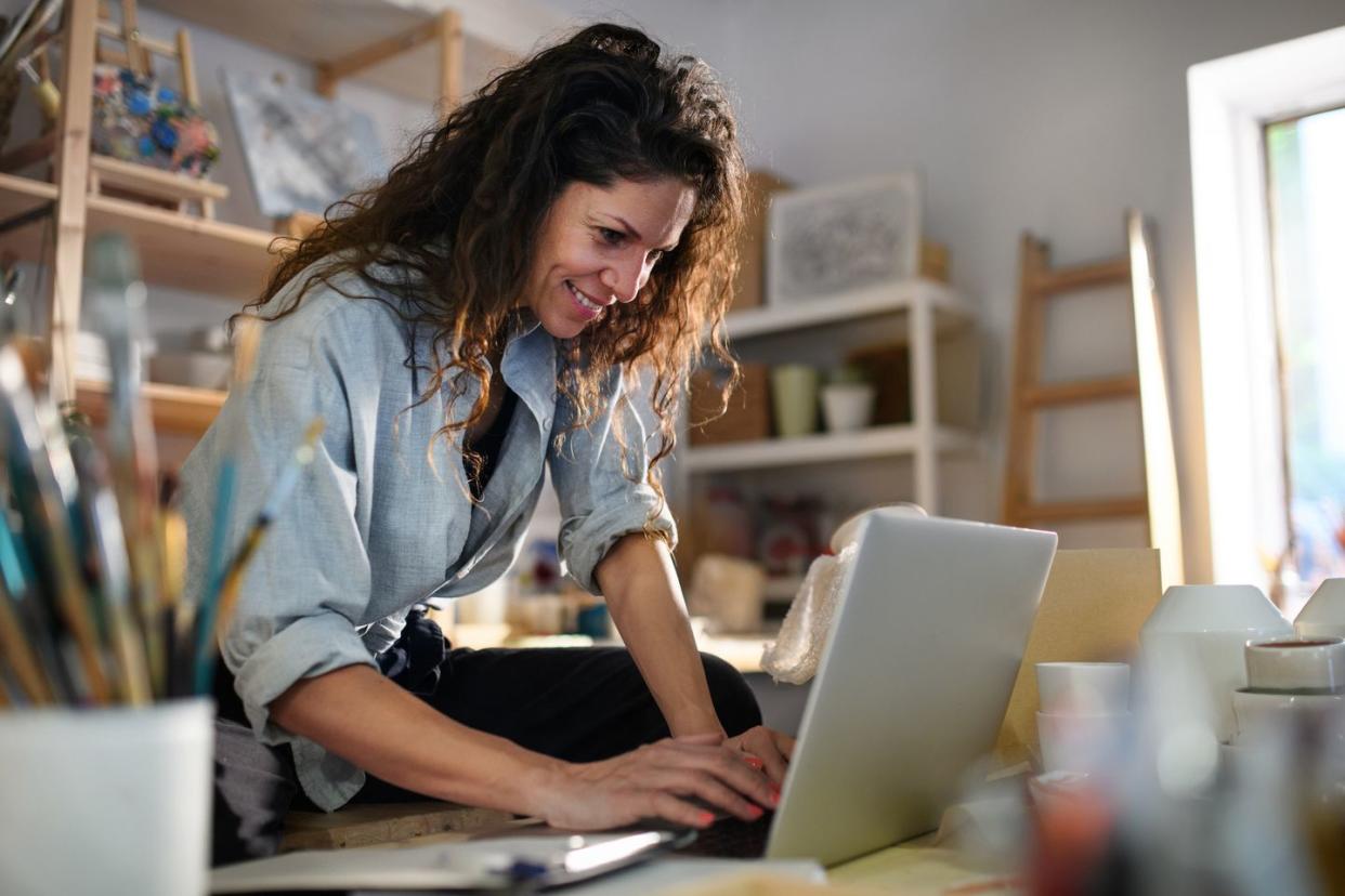 mid adult potter woman, using laptop indoors in art studio small business concept