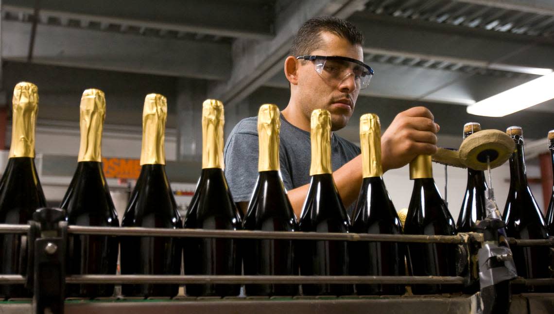 Rodolfo Cardenas puts capsules on bottles of sparkling wine at Laetitia Vineyard and Winery in Arroyo Grande in 2013.