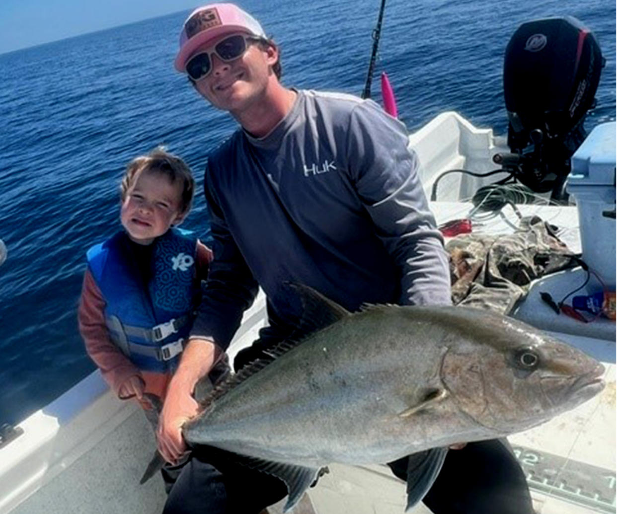 An angler holds up an almaco jack.