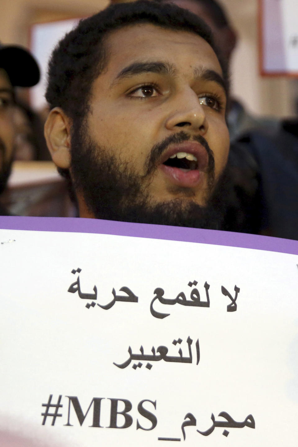 An activist holds up a placard that reads "No to repression of freedom of expression #MBS assassin" on the eve of Saudi Crown Prince Mohammed bin Salman's official visit to Tunisia, during a protest to denounce the killing of Saudi journalist Jamal Khashoggi, in downtown Tunis, Monday, Nov. 26, 2018. (AP Photo/Hassene Dridi)