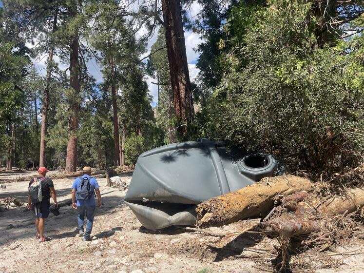 Jason Liou, left, and Rey Cano survey the damage to a water tank at Camp River Glen in the San Bernardino National Forest following Tropical Storm Hilary last August.