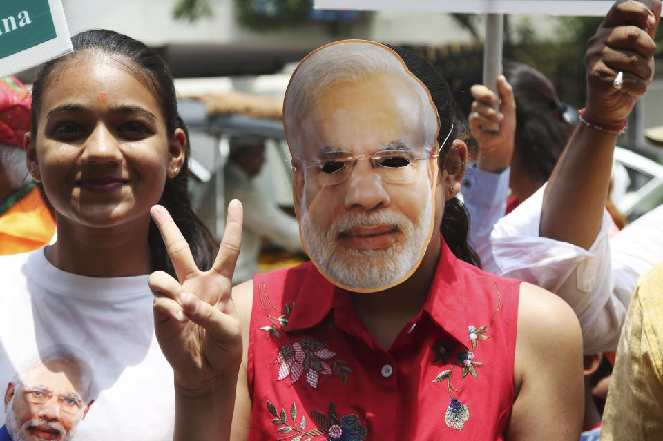 A supporter of India's ruling Bharatiya Janata Party wearing a mask of Indian Prime Minister Narendra Modi shows victory sign as they celebrate early lead in at party's state head quarter in Hyderabad, India, Thursday, May 23, 2019. Modi and his party were off to an early lead as vote counting began Thursday following the conclusion of the country's 6-week-long general election, sending the stock market soaring in anticipation of another five-year term for the Hindu nationalist leader.(AP Photo/Mahesh Kumar A.)