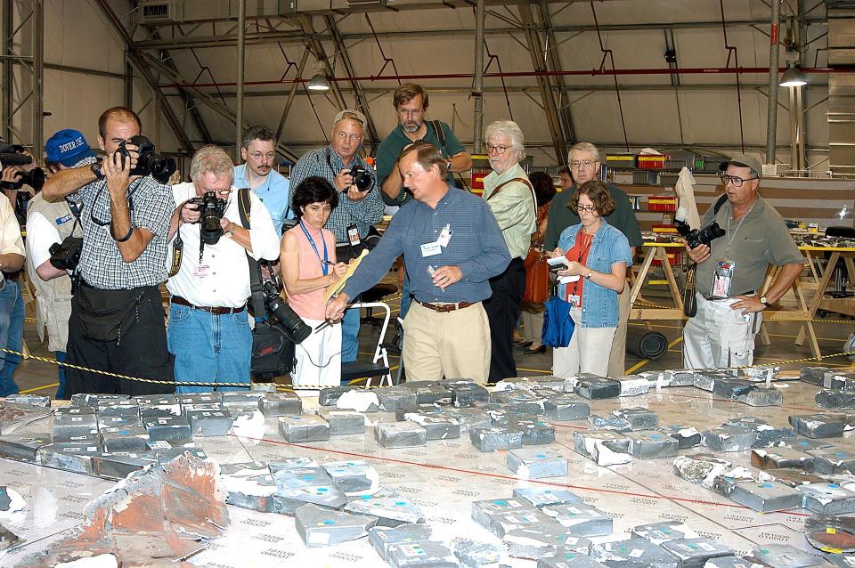 Shuttle Launch Director Mike Leinbach discusses some of Columbia's recovered tiles after the orbiter was lost on Feb. 1, 2003. The hardware seen here was later moved from the Columbia Debris Hangar near the Shuttle Landing Facility to a designated preservation room in the Vehicle Assembly Building.