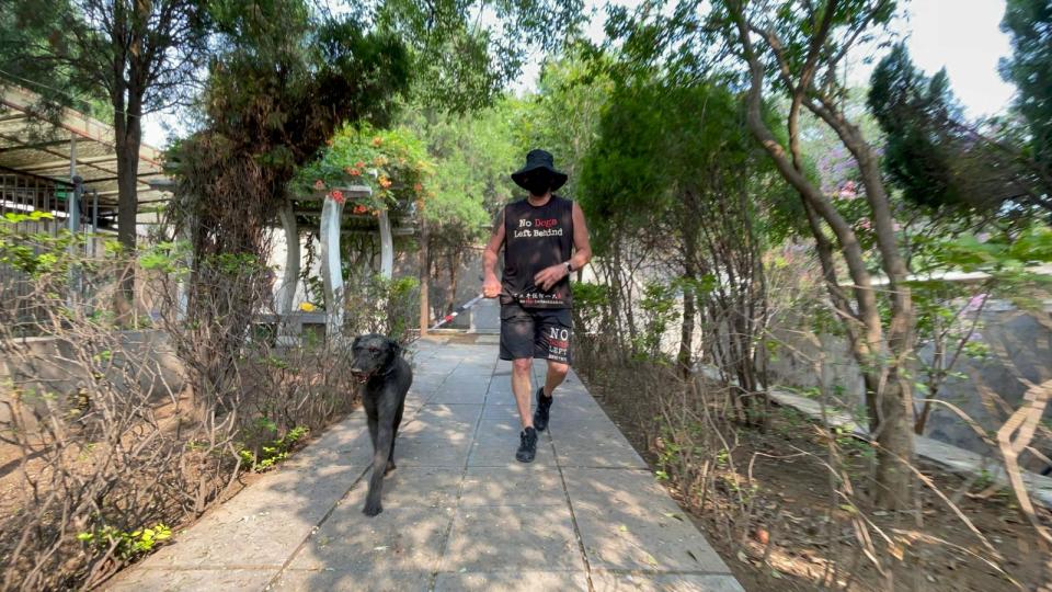 Beri walks a dog at the Gongyi Sanctuary. (Credit: No Dogs Left Behind)