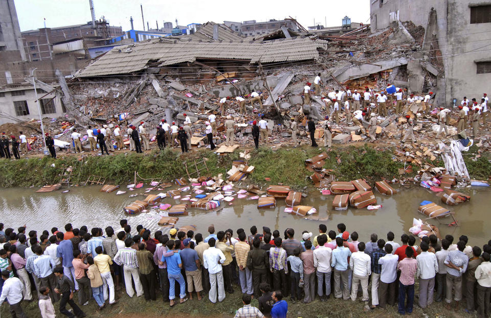 Workers and residents watch rescue operations at the site of a collapsed factory in Jalandhar, India, Monday, April 16, 2012. Several people are feared to be trapped after a three-story building of a factory collapsed after a blast in the factory's boiler, according to local reports. (AP Photo/Altaf Qadri)