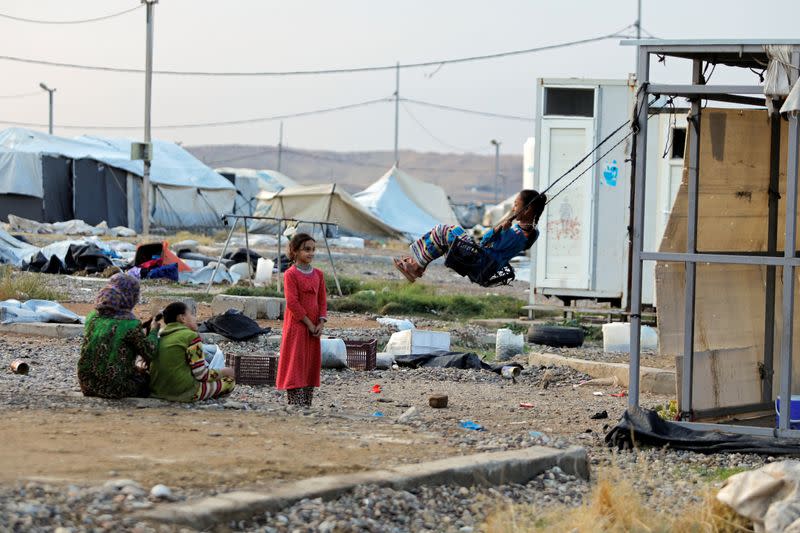 A girl plays on a makeshift swing at Hammam Al-Alil camp where displaced Iraqis prepare to be evacuated, south of Mosul