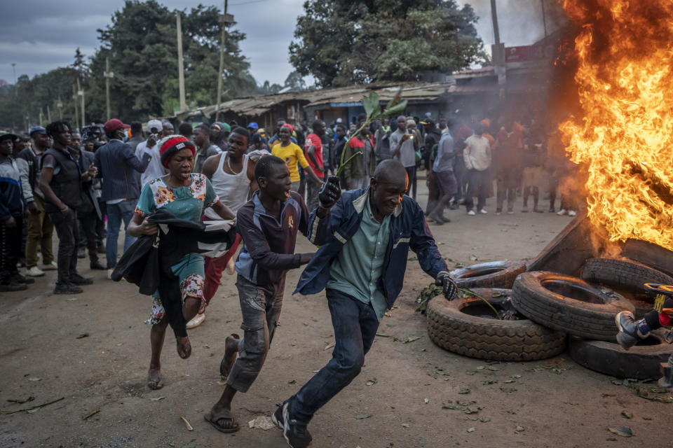 Supporters of presidential candidate Raila Odinga run past a roadblock of burning tires in the Kibera neighborhood of Nairobi, Kenya Monday, Aug. 15, 2022. After last-minute chaos that could foreshadow a court challenge, Kenya's electoral commission chairman has declared Deputy President William Ruto the winner of the close presidential election over five-time contender Raila Odinga. (AP Photo/Ben Curtis)
