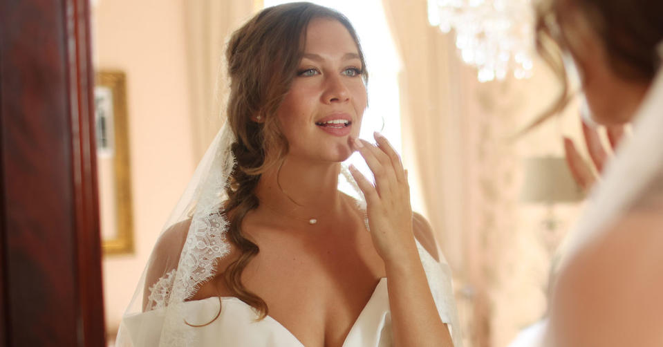 A bride applying lipstick in a mirror