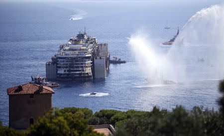 Tugboats spays water in farewell to the cruise liner Costa Concordia during the refloat operation maneuvers at Giglio Island July 23, 2014. REUTERS/ Alessandro Bianchi