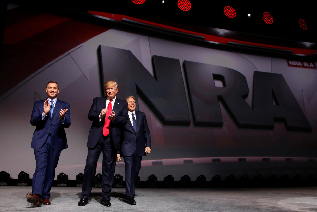 NRA Executive Director Chris Cox, left, and Executive Vice President and CEO Wayne LaPierre, right, welcome President Donald Trump onstage to deliver remarks at the National Rifle Association Leadership Forum in Atlanta on April 28, 2017. (Photo: Jonathan Ernst/Reuters)