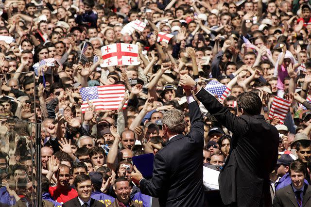 <p>JIM WATSON/AFP via Getty</p> U.S. President George W. Bush, left, holds the hand of Georgian President Mikhail Saakashvili on May 10, 2005, at the event where someone threw a grenade