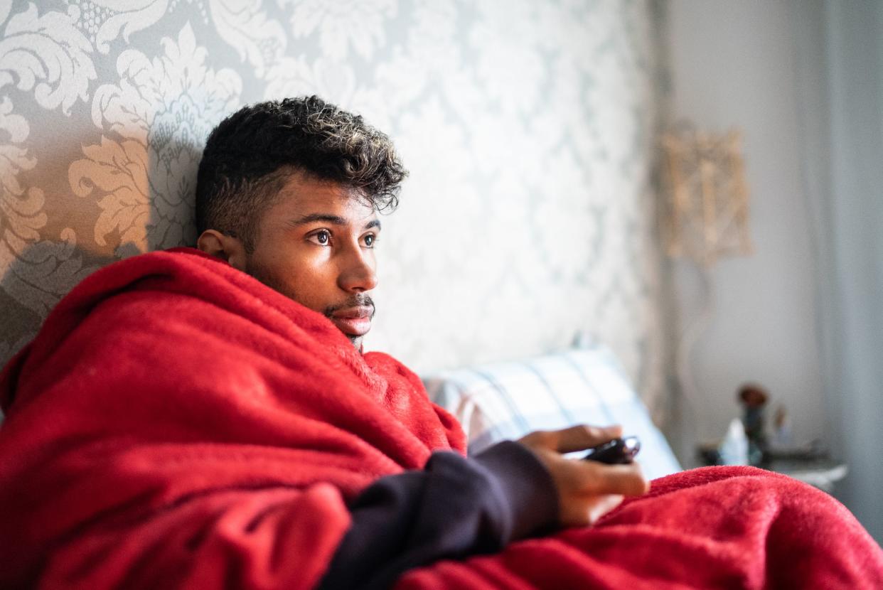 Young man lying down watching TV at home