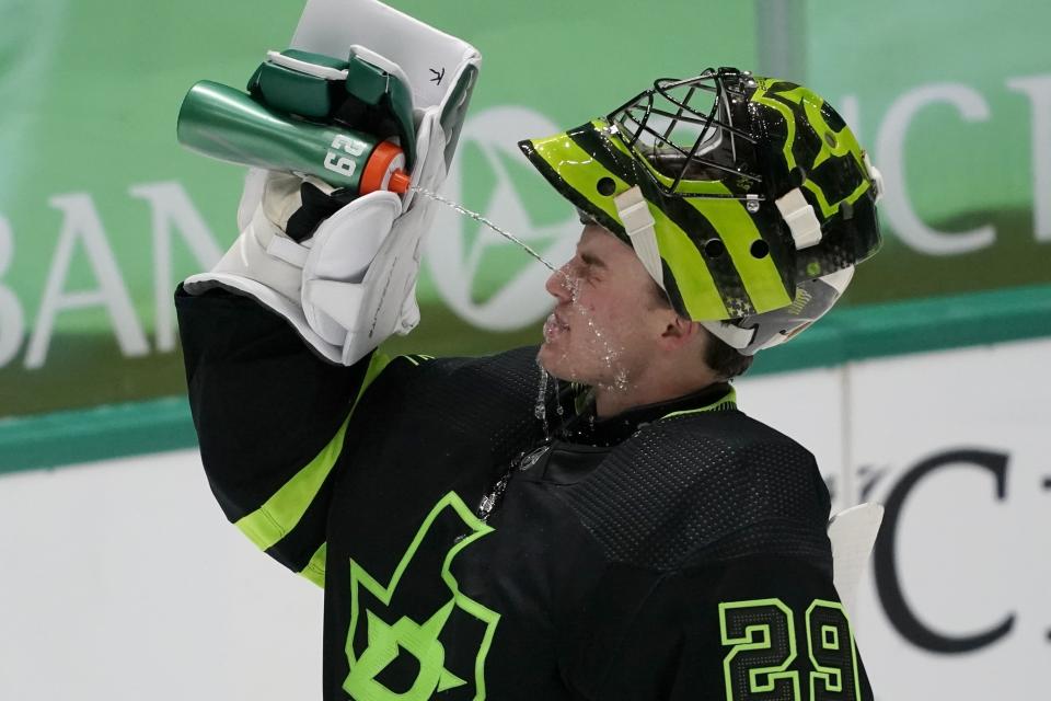 Dallas Stars' Jake Oettinger splashes his face with a drink during a timeout in the second period of the team's NHL hockey game against the Carolina Hurricanes in Dallas, Saturday, Feb. 13, 2021. (AP Photo/Tony Gutierrez)