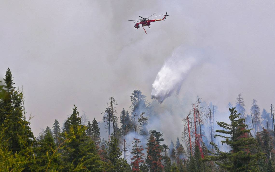 A helicopter drops water on the Washburn Fire as it burns just east of the south entrance to Yosemite National Park Saturday, July 9, 2022 near Oakhurst.