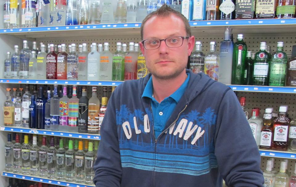 In an Oct. 14, 2013 photo, George Nemetz, manager of Mahoney’s Spirits & Edibles in Traverse City, Mich., stands behind the counter of his downtown shop. Nemetz says town festivals are good for business and disagrees with local residents who think they’ve gotten out of hand. (AP Photo/John Flesher)