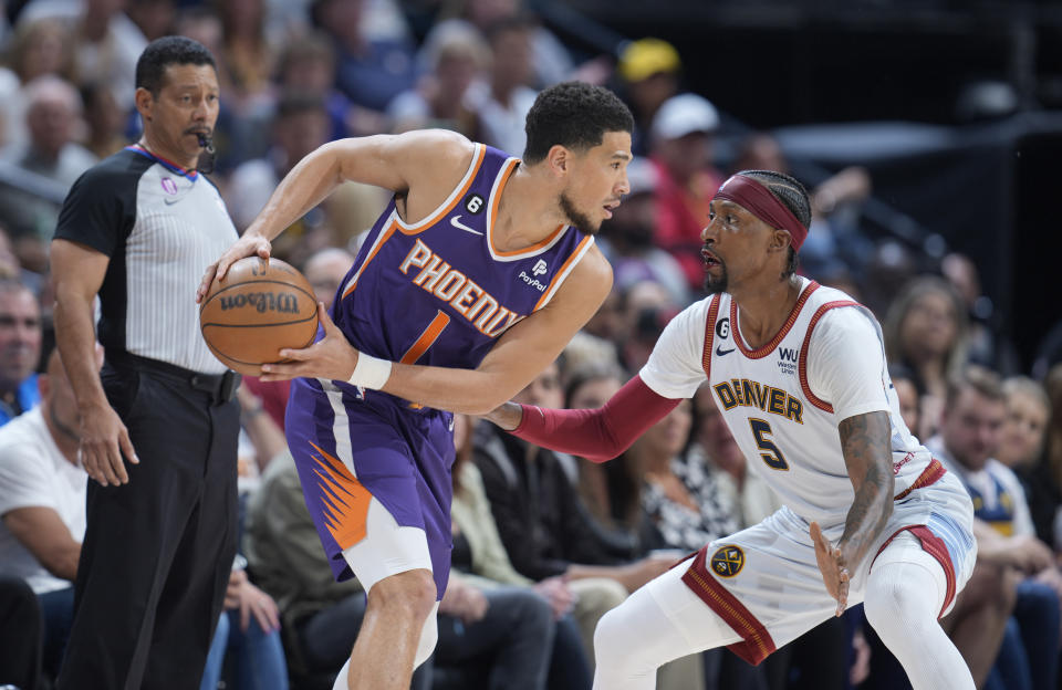 Phoenix Suns guard Devin Booker, left, looks to pass the ball as Denver Nuggets guard Kentavious Caldwell-Pope defends in the first half of Game 5 of an NBA basketball Western Conference semifinal series Tuesday, May 9, 2023, in Denver. (AP Photo/David Zalubowski)