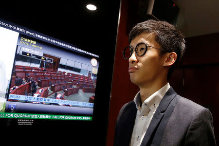 Activist Baggio Leung stands beside a monitor showing a nearly empty chamber after pro-Beijing lawmakers staged a walk-out to stall his swearing-in at the Legislative Council in Hong Kong, China October 19, 2016. REUTERS/Bobby Yip