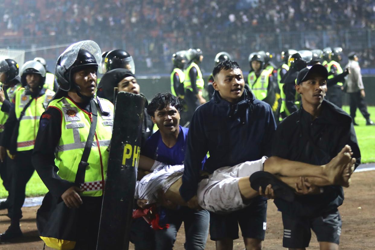 Soccer fans carry an injured man following clashes during a soccer match at Kanjuruhan Stadium in Malang, East Java, Indonesia on Saturday.