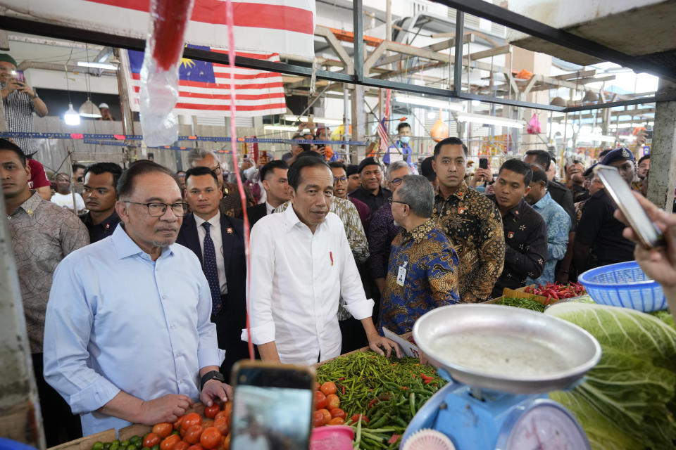 Indonesian President Joko Widodo, center, walks with Malaysian Prime Minister Anwar Ibrahim as they visit a local wet market in Kuala Lumpur, Malaysia, Thursday, June 8, 2023. (AP Photo/Vincent Thian)