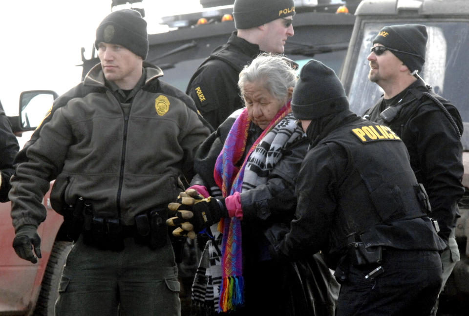 FILE - In this Feb. 23, 2017, file photo, an elderly woman is escorted to a transport van after being arrested by law enforcement at the Oceti Sakowin camp as part of the final sweep of the Dakota Access pipeline protesters in Morton County near Cannon Ball, N.D. Protests and lawsuits against major oil and gas pipeline projects have slowed or stalled projects across the U.S. (Mike McCleary/The Bismarck Tribune via AP, Pool, File)