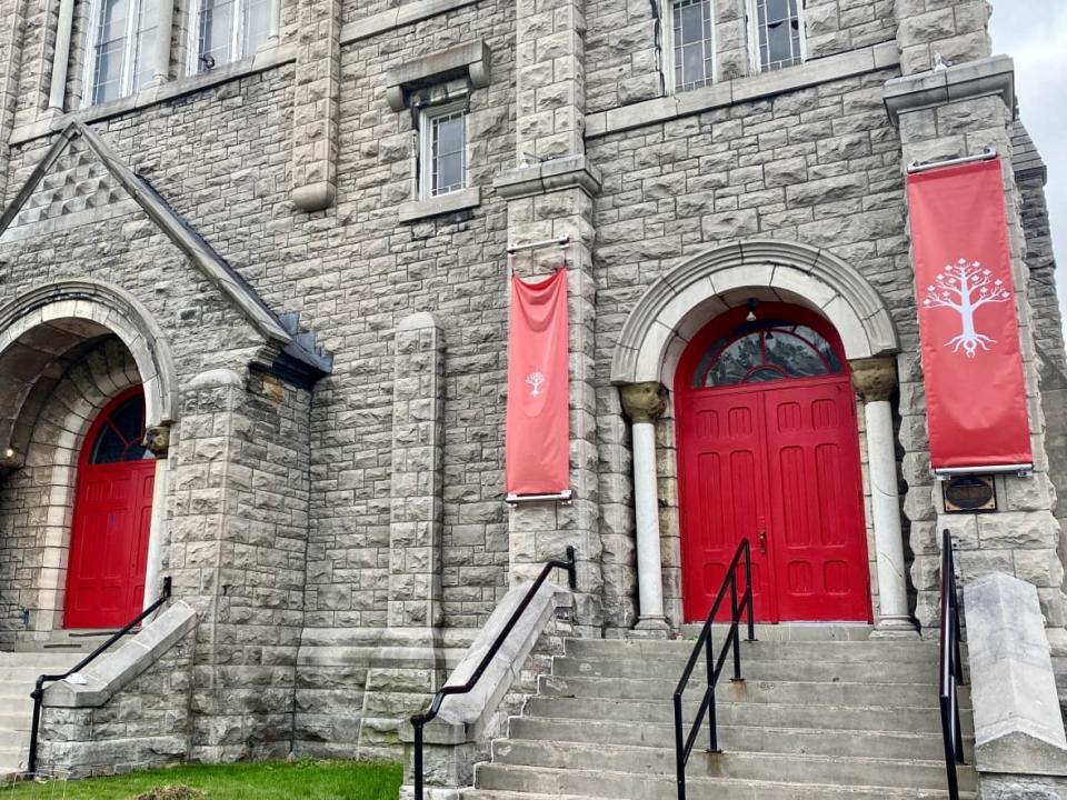 The United People of Canada painted the doors of St. Brigid's red and hung banners bearing a white tree insignia on either side, but the group is being evicted and a bailiff warns the building's locks will soon be changed. (Pierre-Paul Couture/CBC - image credit)