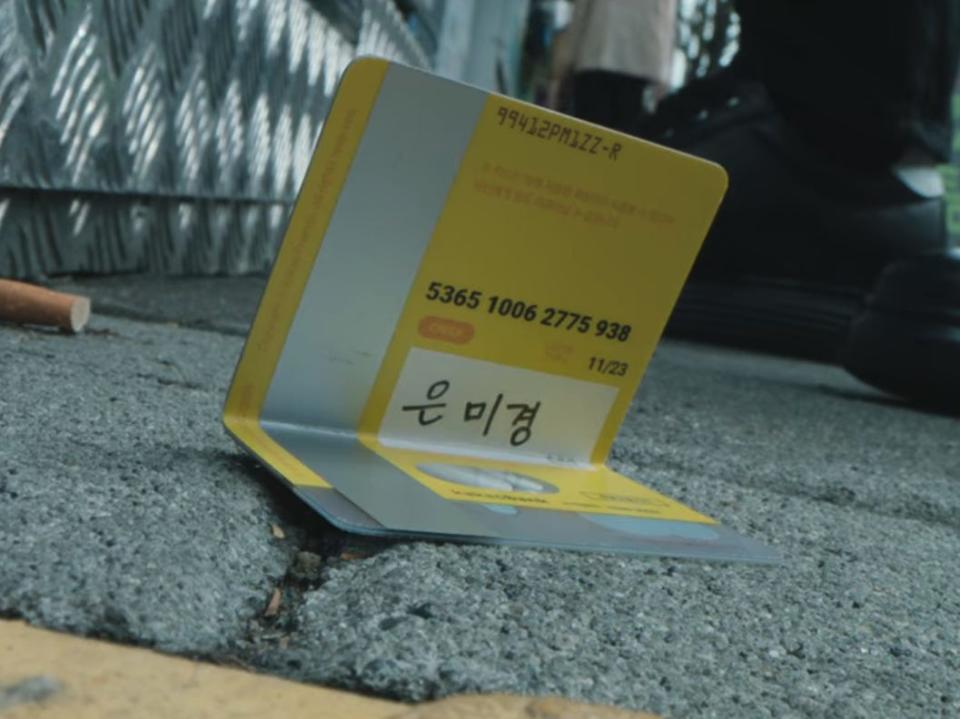 a bent yellow credit card, with the name eun mi-gyeong written on it in hangul in unlocked