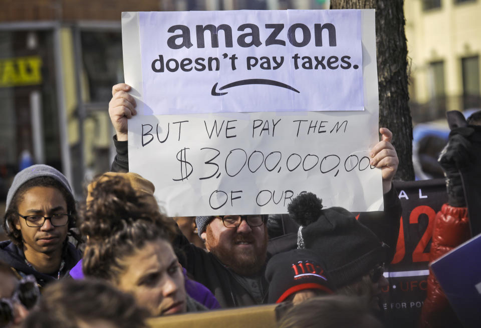 FILE - In this Nov. 14, 2018 file photo, protesters hold up anti-Amazon signs during a coalition rally and press conference of elected officials, community organizations and unions opposing Amazon headquarters getting subsidies to locate in Long Island City, in New York. Local resistance to the online retailer building part of its headquarters in Long Island City was almost immediate. (AP Photo/Bebeto Matthews, File)