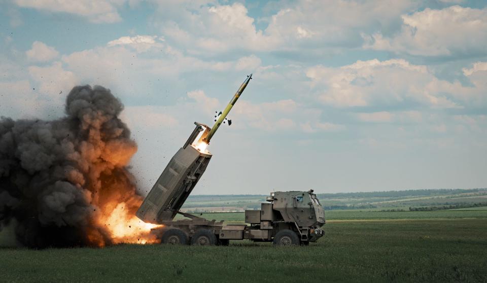 A M142 HIMARS rocket being fired in a field.