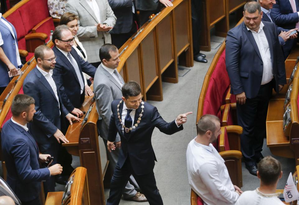 In this photo taken on Monday, May 20, 2019, Ukrainian new President Volodymyr Zelenskiy, centre, leaves the parliament after his inauguration ceremony in Kiev, Ukraine. Ukrainian TV star Volodymyr Zelenskiy was sworn in as the country's new president on Monday, and promised to stop the war in the country's east against Russian-backed separatists and immediately disbanded parliament, which he has branded as a group only interested in self-enrichment. (AP Photo/Efrem Lukatsky)