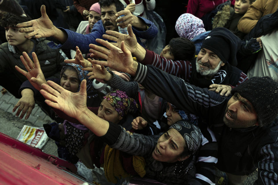 Volunteers distribute aid to people in Antakya, southern Turkey, Wednesday, Feb. 8, 2023. Thinly stretched rescue teams worked through the night into Wednesday, pulling more bodies from the rubble of thousands of buildings downed in Turkey and Syria by a catastrophic earthquake. (AP Photo/Khalil Hamra)