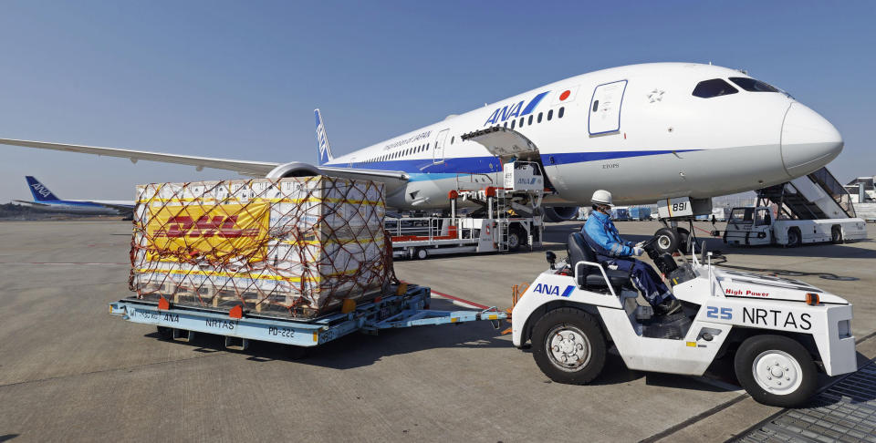 A man moves containers of coronavirus vaccine imported by an All Nippon Airways airplane after it arrived at Narita International Airport in Narita, east of Tokyo on Sunday, Feb. 21, 2021. (Kenzaburo Fukuhara/Kyodo News via AP)