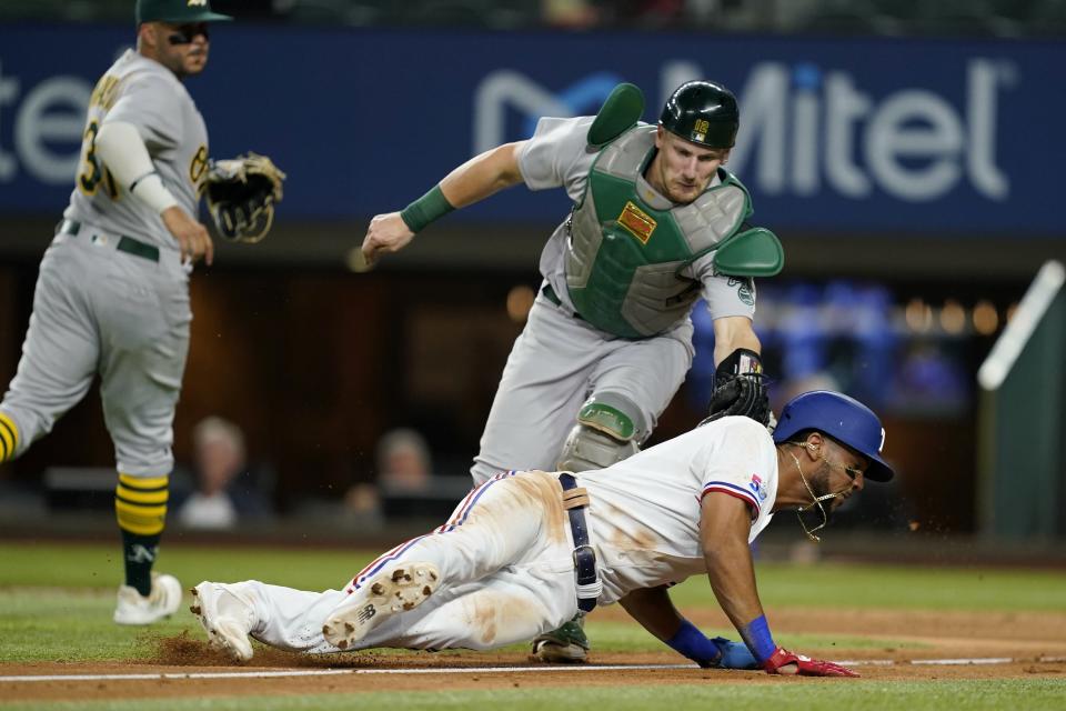 Texas Rangers' Leody Taveras is tagged out by Oakland Athletics catcher Sean Murphy in a rundown when Taveras tried to score on a Marcus Semien flyout in the fifth inning of a baseball game in Arlington, Texas, Tuesday, Aug. 16, 2022. Athletics' Vimael Machin is at left. (AP Photo/Tony Gutierrez)