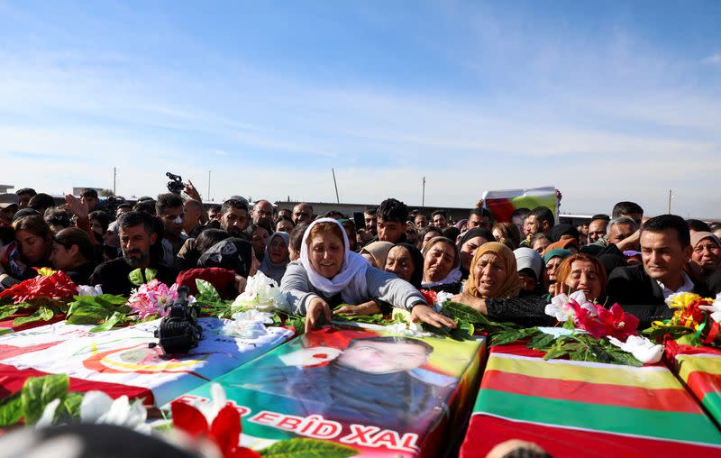 People mourn near coffins during a funeral in Derik countryside