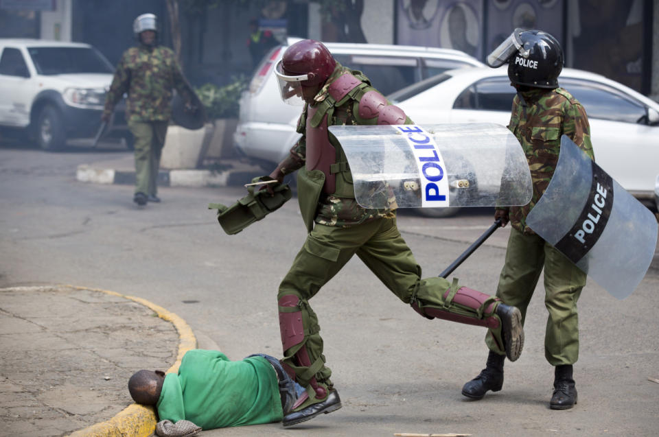 A Kenyan riot policeman repeatedly kicks a protester as he lies in the street after he tripped while trying to flee from them during a protest in downtown Nairobi, Kenya, May 16, 2016. Kenyan police have tear-gassed and beaten opposition supporters during a protest demanding the disbandment of the electoral authority over alleged bias and corruption. (AP Photo/Ben Curtis)
