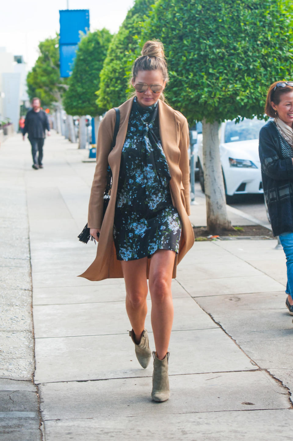 Chrissy Teigen wears a floral mini dress and camel coat on Nov. 24, 2015 in Los Angeles, California.