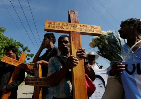 Relatives of missing students of the Ayotzinapa Teacher Training College, Raul Isidro Burgos, participate in a march as they carry crosses with the names of three students who were killed during clashes with police in late September, in Iguala October 27, 2014. REUTERS/Henry Romero