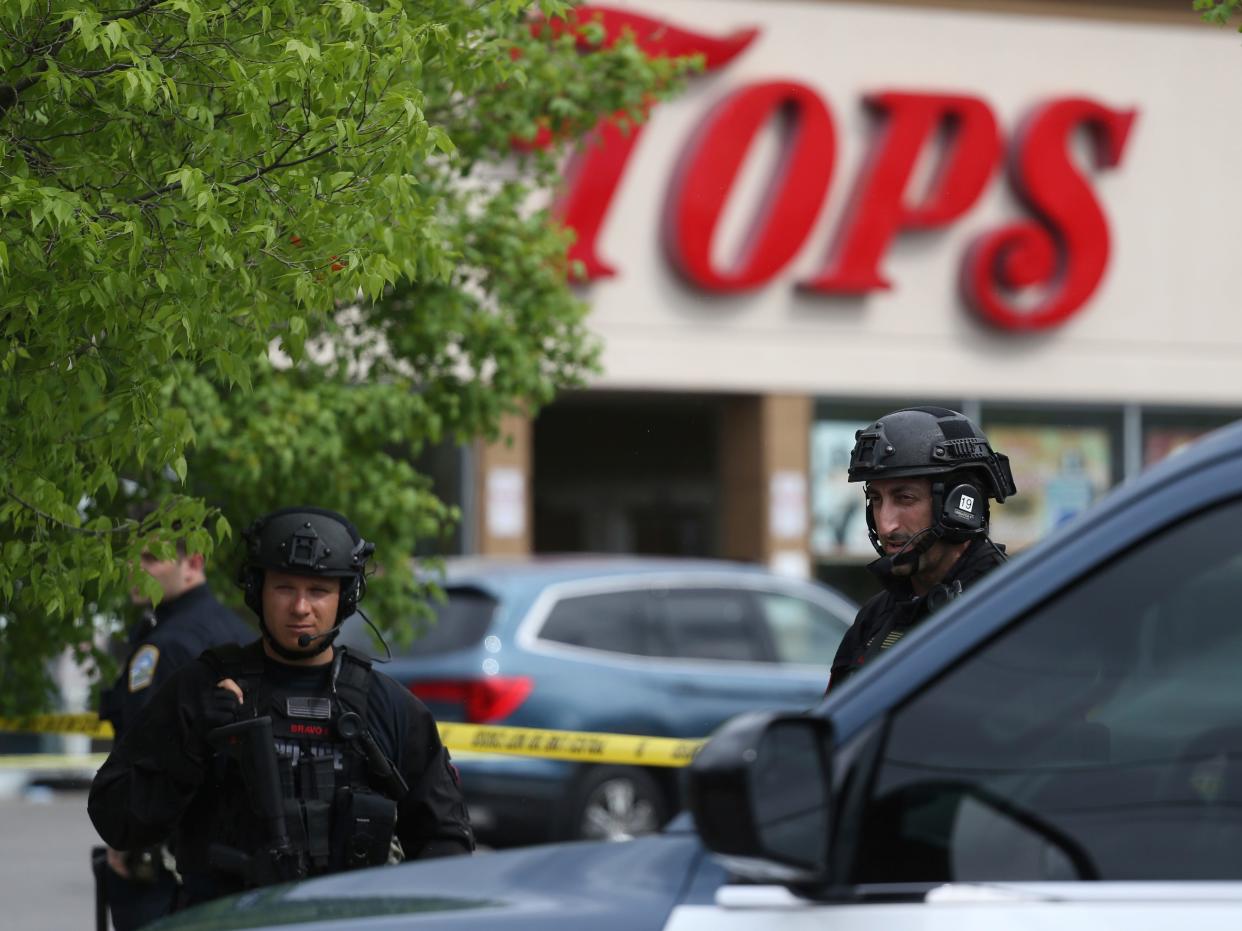 A police officer looks out a store window as authorities investigate a shooting at the supermarket, Saturday, May 14, 2022, in Buffalo, N.Y.