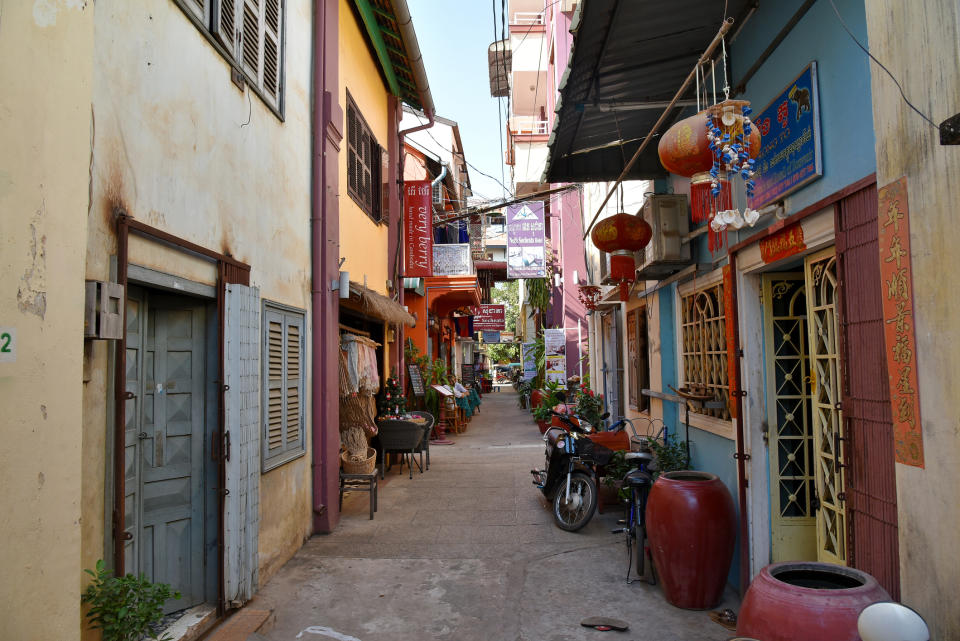 Narrow alley with motorcycles parked and buildings on either side; lanterns hang above