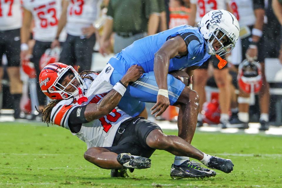 Nov 11, 2023; Orlando, Florida, USA; UCF Knights wide receiver Javon Baker (1) is tackled by Oklahoma State Cowboys cornerback Kale Smith (10) during the second quarter at FBC Mortgage Stadium. Mandatory Credit: Mike Watters-USA TODAY Sports