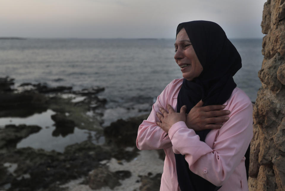 Lebanese Afaf Adulhamid the mother of Mohammed Khaldoun, 27, who is still missing at sea while he was trying with other migrants to reach Cyprus on a boat, cries and prays her son's safe return, as she stands on the coast of Tripoli city, north Lebanon Thursday, Sept. 17, 2020. Mohammed is one of scores of people who have tried in recent weeks to flee Lebanon that is passing through its worst economic and financial crisis in decades to European Union member Cyprus. (AP Photo/Hussein Malla)