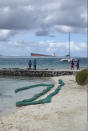 In this still image taken from video provided by Grégoire Rouxel, people watch a ship that ran aground offshore that is leaking fuel, Friday, Aug. 7, 2020, in Mauritius. The Indian Ocean island of Mauritius has declared a "state of environmental emergency" after a Japanese-owned ship that ran aground offshore days ago began spilling tons of fuel. Prime Minister Pravind Jugnauth announced the development late Friday, as satellite images showed a dark slick spreading near environmental areas the government called "very sensitive." (@gregrouxel via AP)